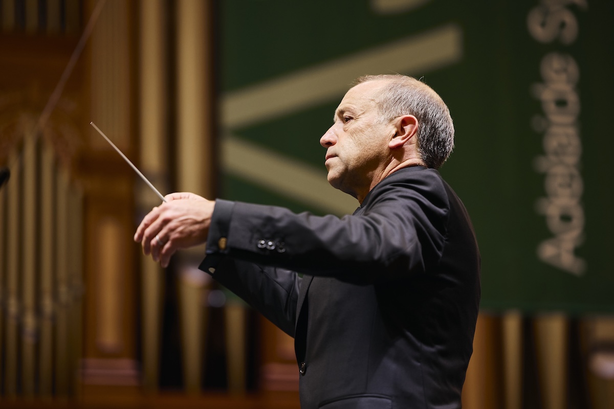 Conductor Mark Wigglesworth holding a baton in mid-performance on stage with the Adelaide Symphony Orchestra. Photo by Claudio Raschella.